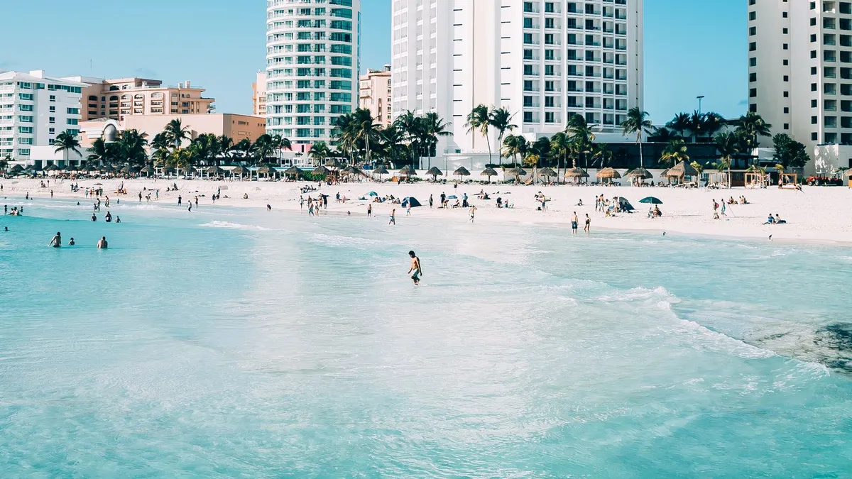 Turquoise water, white sand, and beachfront towers under a blue sky